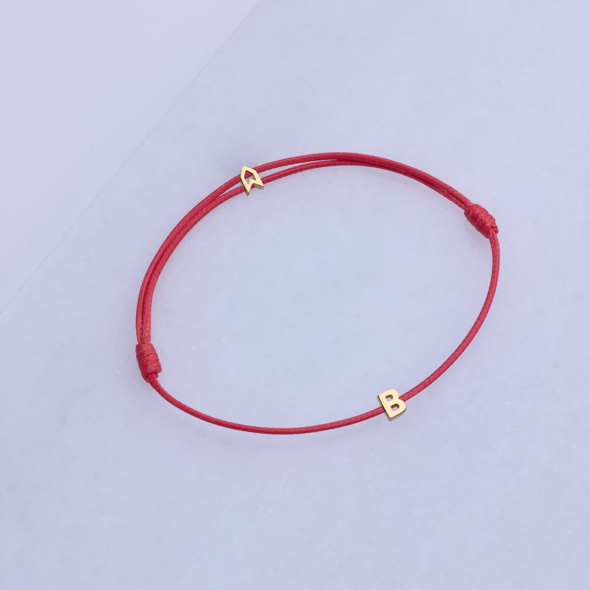 Altın renginde, kırmızı alfabe harflerinden oluşan şans bileziği.