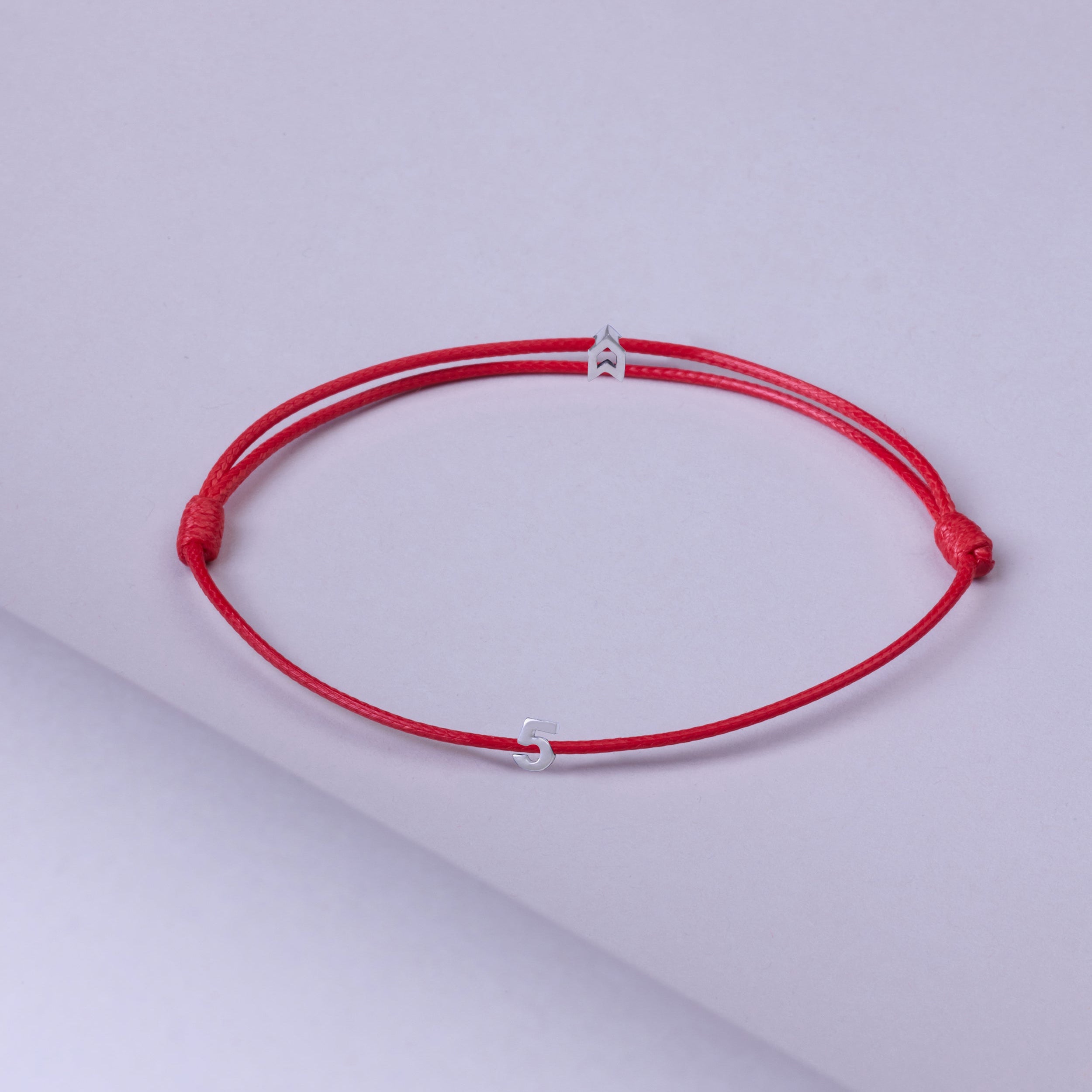 Gümüşten yapılmış, üzerinde kırmızı rakamlar bulunan, şans sembolü içeren bileklik.