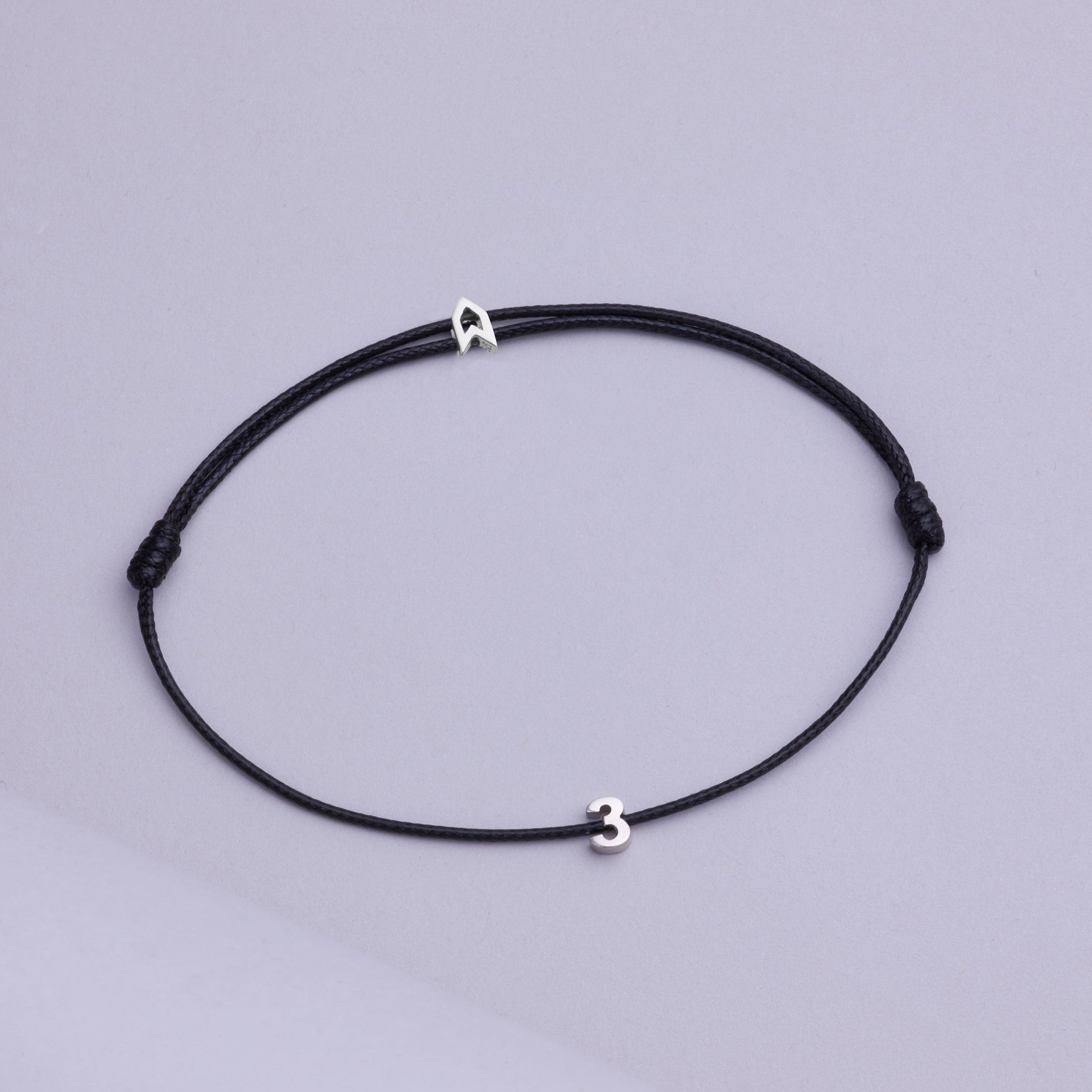 Gümüşten yapılmış, siyah renkli, sayısal sembollü şans bileziği.